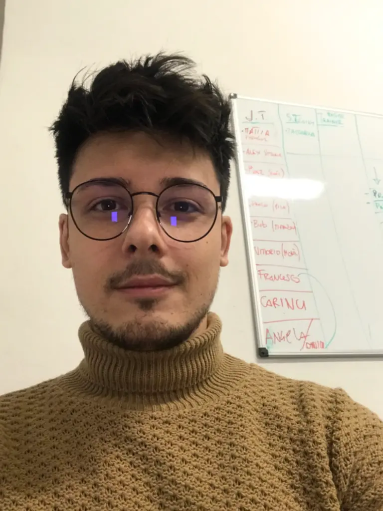 Angelo nel 2019, con gli occhiali, davanti a una lavagna di appunti