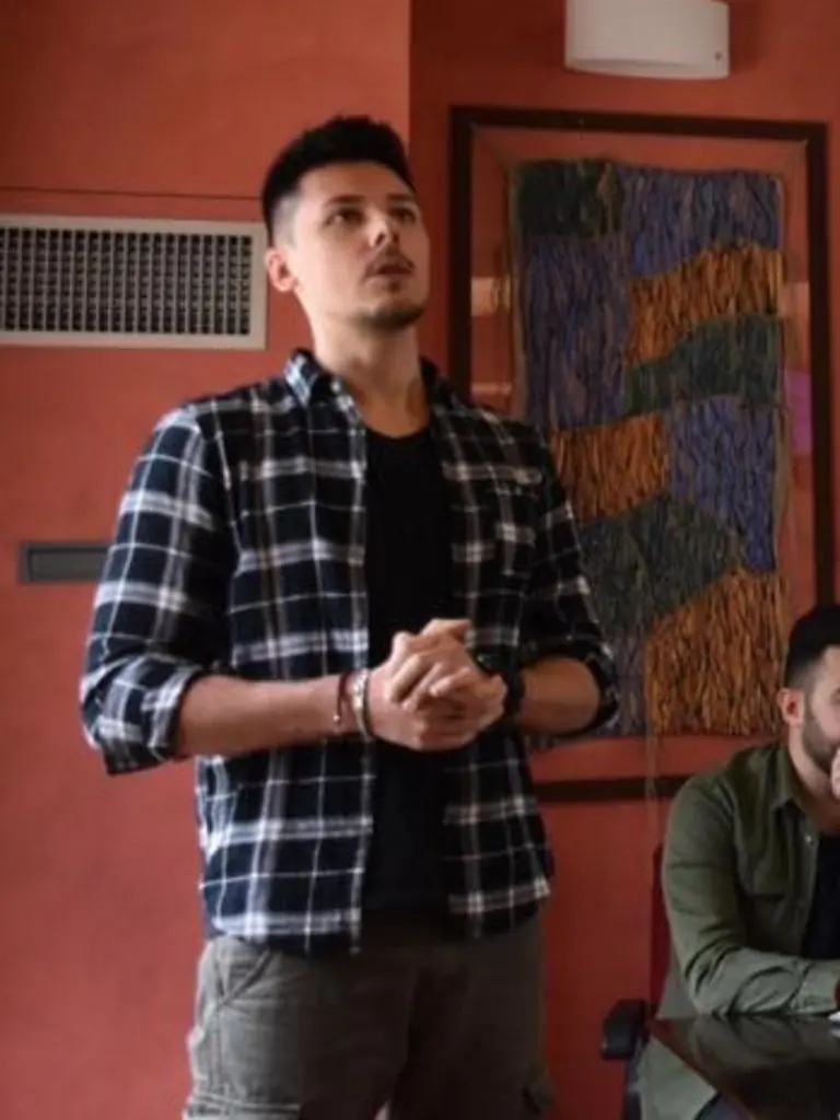 Angelo parla in aula, con la camicia a quadri