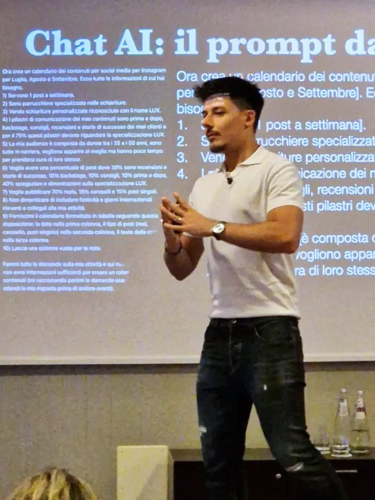 Angelo sul palco in maglietta bianca, davanti a una slide sul prompt